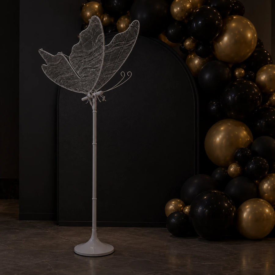 Lampa Motyl LED zgaszona przy ścianie z czarnymi i złotymi balonami